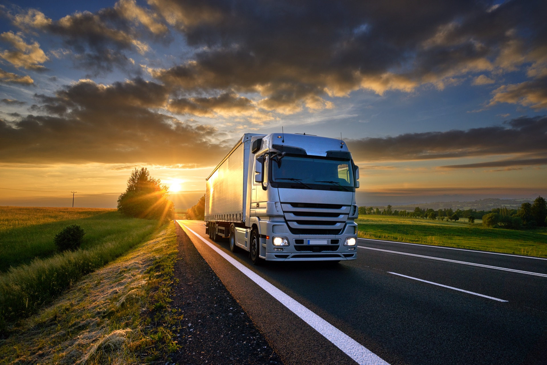 lorry driving up road with golden sunset in the distance