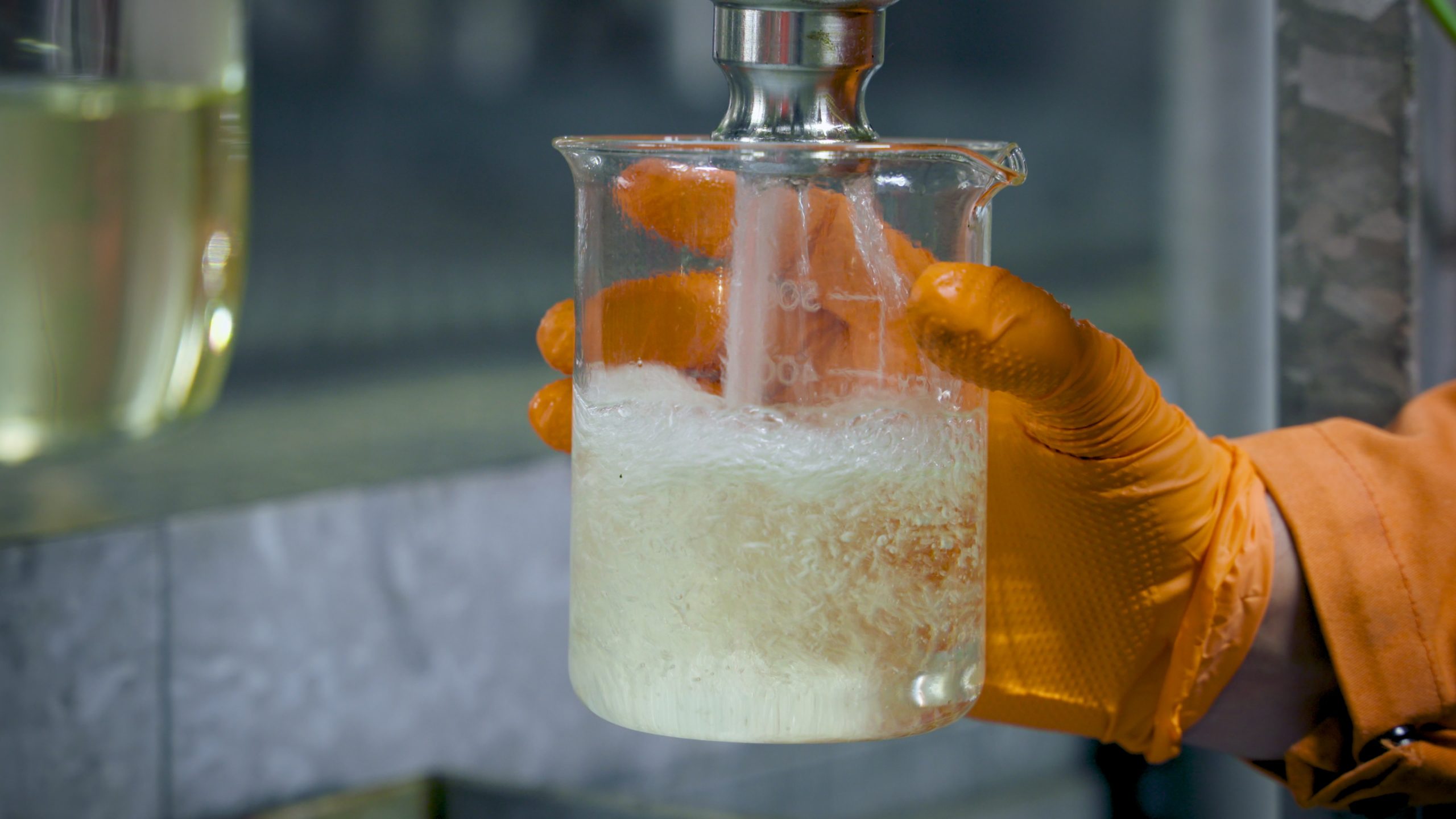 collecting biodiesel sample in glass beaker